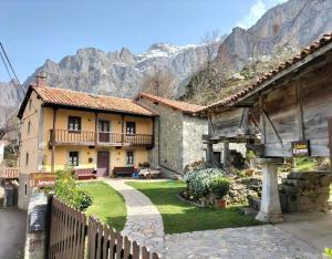a house with a garden and mountains in the background at El Jermoso in Posada de Valdeón