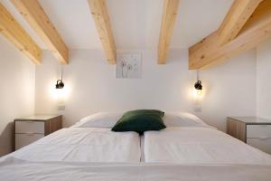 a bedroom with a white bed with a green pillow at Cà Dei Nane Vermiglio in Vermiglio