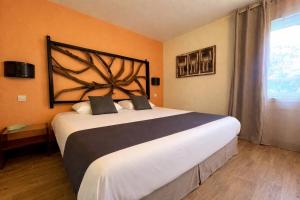 a bedroom with a large bed in a room at Logis Hôtel Les Grenadines in Cap d'Agde