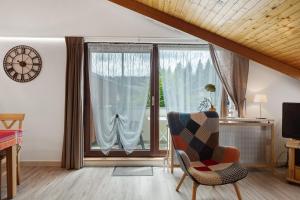 a living room with a chair and a large window at Gästehaus Himmelswiese Ingo Reetz in Schönwald