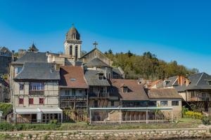 a group of houses with a clock tower on a hill at La Noyeraie - Chambre d'hotes in Saint-Amand-de-Coly