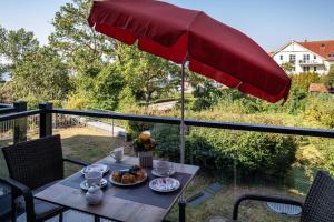 a table with a red umbrella on a balcony at Ferienwohnung Am Salzhaff B6 in Rerik
