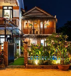 a house with a balcony and plants in front of it at Family Private Villa Hội An in Hoi An