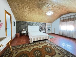 a bedroom with a white bed and a rug at Refugio Senhora Paz in Marinhas