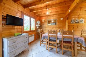 a dining room with a table and a television in a cabin at Notre chalet in Vecoux
