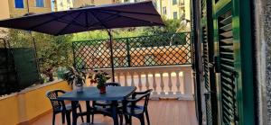 a table and chairs on a balcony with an umbrella at Casa vacanza Teresita 300mt Mare in Imperia