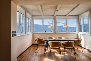 a dining room with a table and chairs and windows at Kraidlhof Designapartment Isabel in Cortaccia