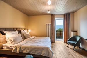 a bedroom with a bed and a chair and a window at Kraidlhof Designapartment Isabel in Cortaccia