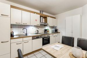 a kitchen with white cabinets and a table and chairs at Ferienwohnung Rinke in Schmallenberg