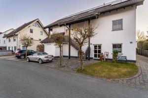 a white house with a car parked in front of it at Ferienwohnung Rinke in Schmallenberg