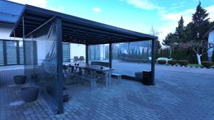 ein Pavillon mit Tisch und Bänken auf einer Terrasse in der Unterkunft Bele House in Karmėlava