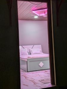 a small white bed in a room with a pink light at Gawkari Hillside Agroturism in Satara