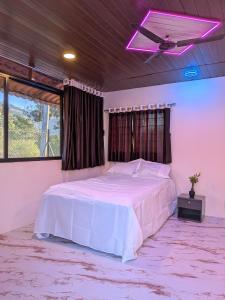 a bedroom with a white bed with a purple light at Gawkari Hillside Agroturism in Satara