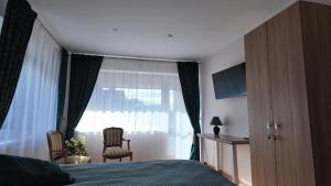 ein Schlafzimmer mit einem Bett und einem Fenster mit zwei Stühlen in der Unterkunft Bele House in Karmėlava