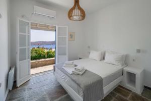 a white bedroom with a bed and a balcony at Bella Vista Vacation House in Serifos Chora