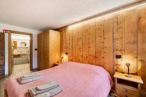 a bedroom with a pink bed and wooden walls at Les Cles - Genepy in Valsavarenche