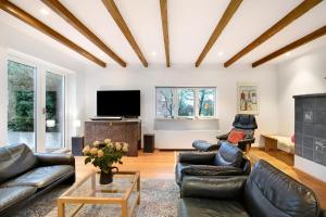 ein Wohnzimmer mit Ledermöbeln und einem Flachbildfernseher in der Unterkunft Olendeel in Gelting