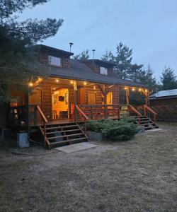 a large log cabin with a porch and lights on it at Domki Anastazewo in Anastazewo