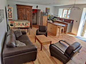 a living room with a brown couch and a kitchen at Longère de charme in Kervignac