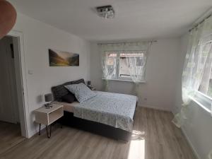 a white bedroom with a bed and a window at Ferienwohnung bei Bojko in Oberkirch