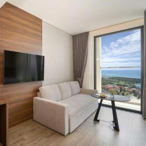 a living room with a couch and a tv and a table at Apec Beach Luxury Phú Yên in Tuy Hoa