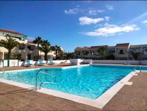 a large swimming pool with blue chairs and buildings at Torres in Antigua