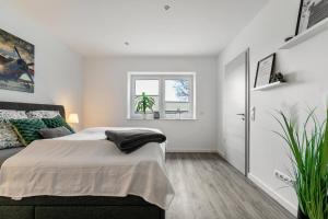 a white bedroom with a bed and a window at Mika in Oesterdeichstrich