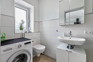a white bathroom with a washing machine and a sink at Mika in Oesterdeichstrich +16 photos