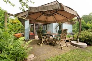 a patio with a table and chairs under an umbrella at Ferienhaus Karlsminde in Waabs