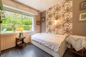 a bedroom with a bed and a window at Ty Clafout wifi parking in Saint-Nolff