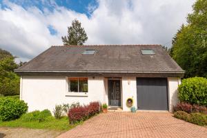 a white house with a black door on a brick driveway at Ty Clafout wifi parking in Saint-Nolff