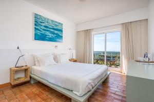 a white bedroom with a bed and a large window at Alto da Lua in Bordeira +101 photos