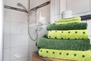 a stack of green towels on a shelf in a bathroom at Ferienwohnung Wendelinus in Rettenberg +12 photos