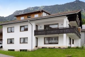 a white house with a balcony on top of it at Ferienwohnung Wendelinus in Rettenberg
