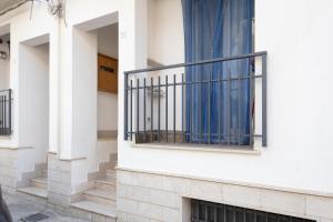 a white building with a balcony with blue curtains at Casavacanzefranca - 12 in Terrasini