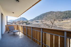 a balcony with a chair and mountains in the background at sunnig Apartment Sonnenlicht in Vollan +11 photos