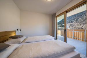 two beds in a bedroom with a large window at sunnig Apartment Sonnenlicht in Vollan