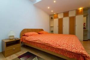 a bedroom with a bed with a orange bedspread and a night stand at Михайловская in Kyiv +3 photos
