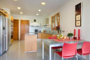 a kitchen with a table and red chairs in it at Villa Golf Marina Premium in Pollença