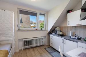 a small kitchen with white cabinets and a window at Mini Apartment in Bayreuth