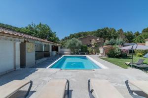 a swimming pool in a yard with benches and a house at Domaine du Courroussouve in Oppède