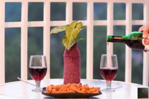 a person pouring wine into a red vase with a plant in it at Himalayan Mist Retreat By Cloud Berry stays kasauli in Dharampur