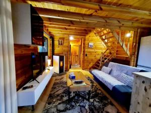a living room with a couch and a tv at Le Chalet Aura et Jacuzzi in Abreschviller