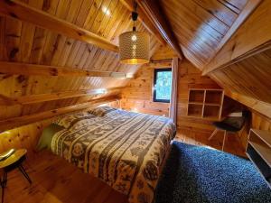 a bedroom with a bed in a wooden cabin at Le Chalet Aura et Jacuzzi in Abreschviller