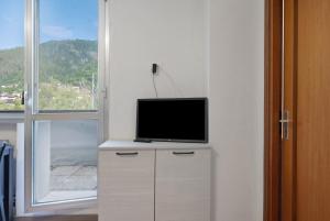 a tv sitting on a dresser in a room with a window at Marilleva 900 Kristall in Mezzana