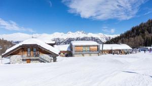 a building covered in snow with mountains in the background at Marilleva 900 Kristall in Mezzana