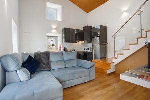 a living room with a blue couch and a kitchen at Residencia Dos Castelos in Santarém