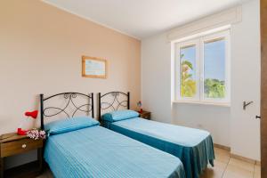 two beds in a room with a window at Residence Punta Pizzo in Marina di Mancaversa