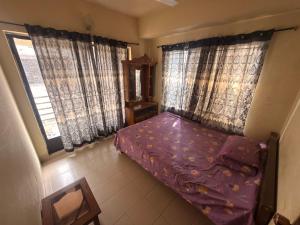 a small bedroom with a bed and two windows at Garden tower,sylhet in Sylhet
