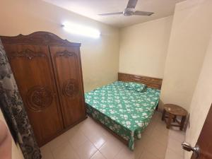 a small bedroom with a bed and a wooden cabinet at Garden tower,sylhet in Sylhet